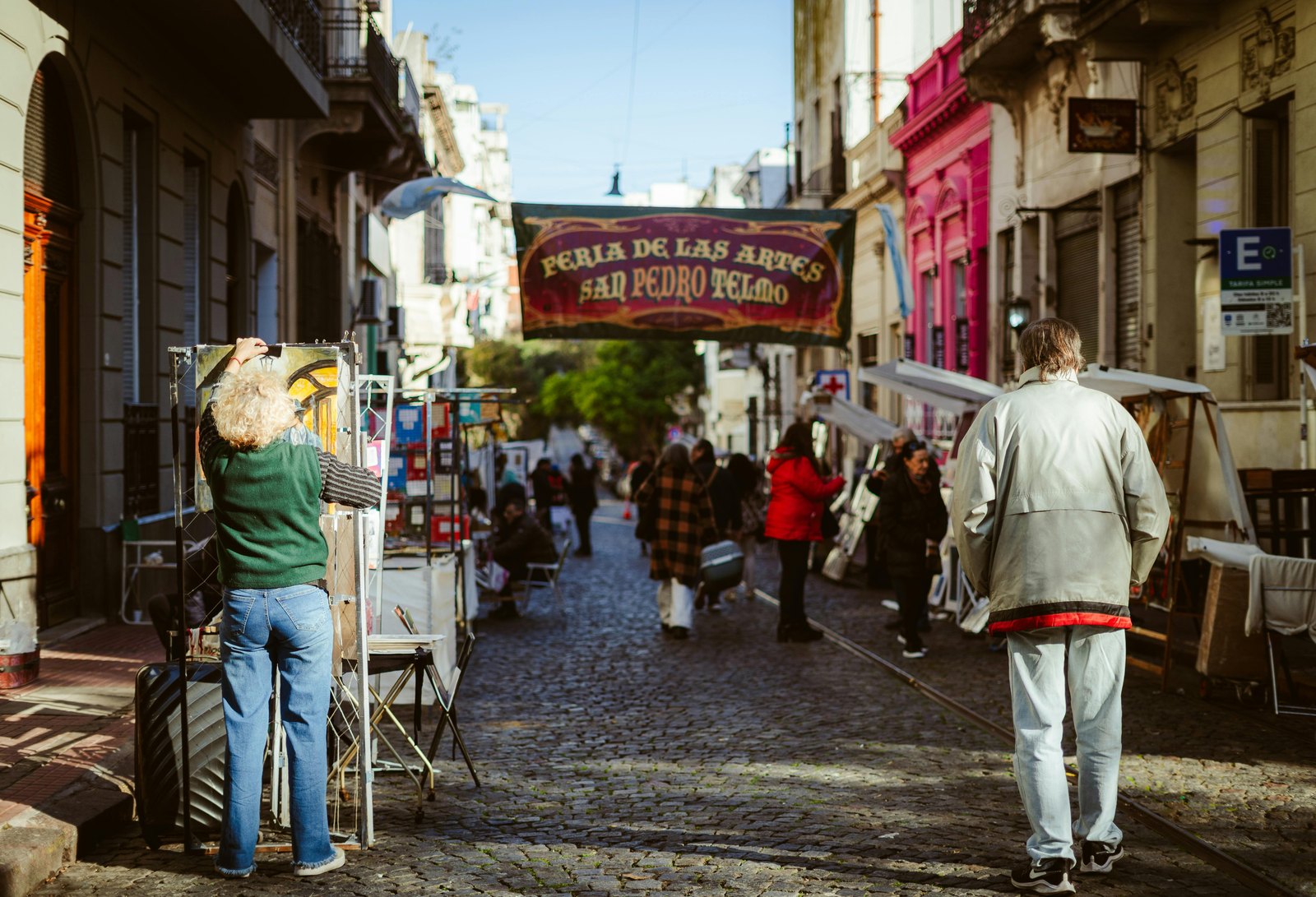 Feria de artes callejera en San Telmo, con un artista pintando en la calle.