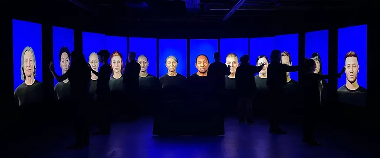 «Cientos de millones de años para estas formas»: trece pantallas en semicírculo con las figuras de un coro sobre fondo azul.